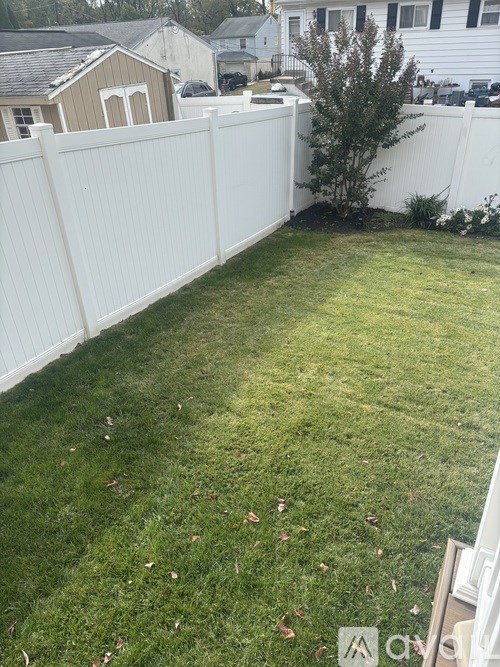 A backyard with a white fence and a green lawn.