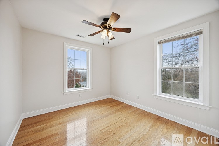 A room with a ceiling fan and two windows.