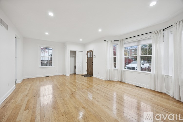 A spacious room with wooden floors and white walls.