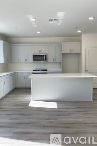 A modern kitchen with a white island and wooden floors.