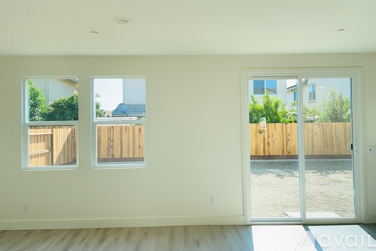A room with two windows and a sliding glass door.