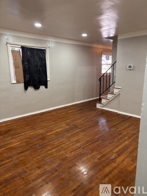 A room with wooden flooring and a black jacket hanging on the wall.