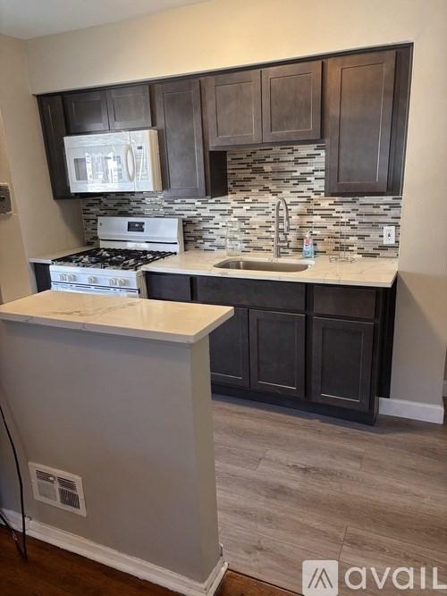 A kitchen with a white counter top and dark brown cabinets.
