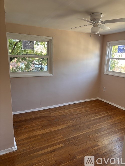 A room with wooden floors and two windows.