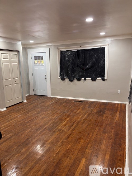 A room with wooden flooring and two doors.