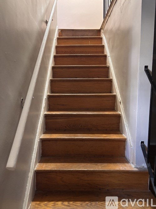 A set of wooden stairs with a metal handrail.