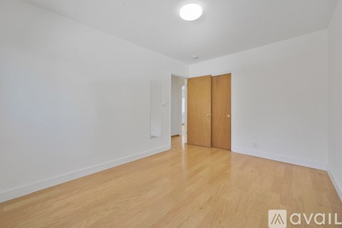 A room with wooden flooring and two doors.