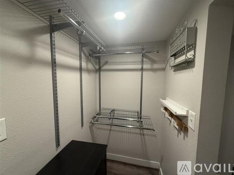 A walk-in closet with shelving and a black bench.