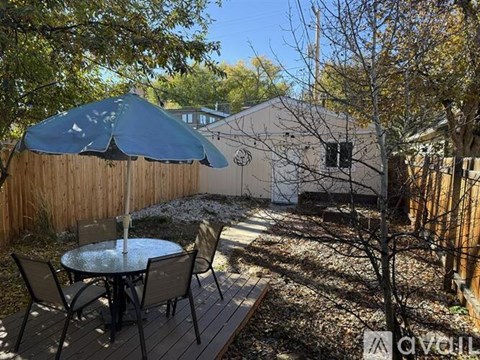 A patio with a table and chairs and a blue umbrella.