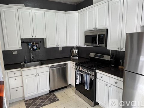 A kitchen with white cabinets and black countertops.