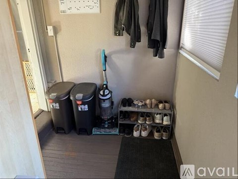 A hallway with a rack of shoes and two trash bins.