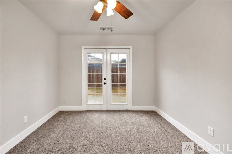 A room with a ceiling fan and a door with a glass window.