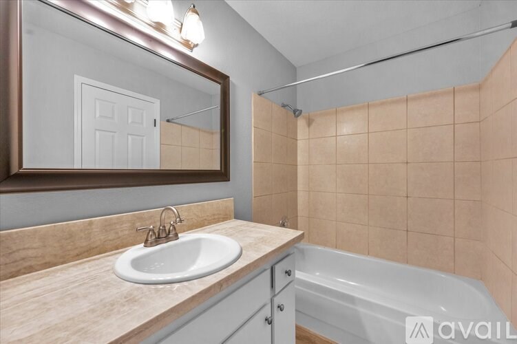 A bathroom with a sink, mirror, and bathtub.