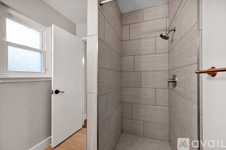 A bathroom with a walk in shower and a window.