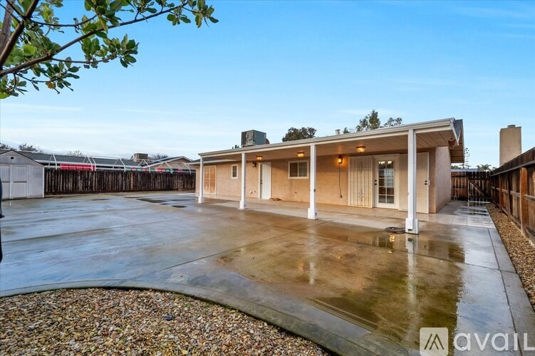 A house with a driveway and a tree branch in the foreground.