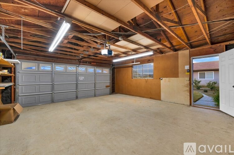 A spacious garage with a high ceiling and a view of the backyard through the open door.