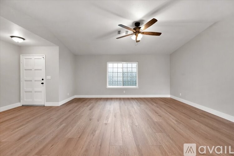 A room with a ceiling fan and wooden flooring.