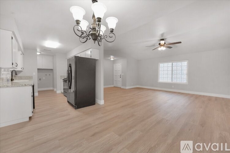 A spacious kitchen with a refrigerator, a ceiling fan, and a chandelier.