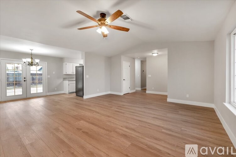 A spacious room with wooden flooring and a ceiling fan.