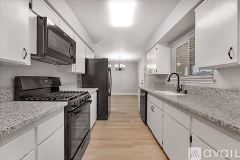 A kitchen with white cabinets and black appliances.