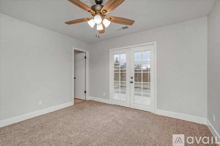 A room with a ceiling fan and carpeted floor.