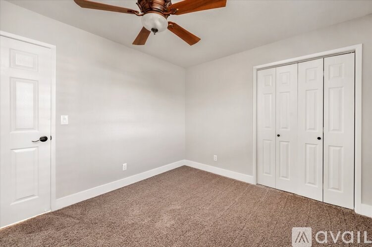 A room with a ceiling fan and two doors.