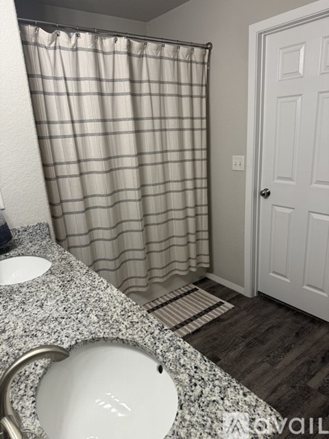 A bathroom with a checkered shower curtain and a white door.