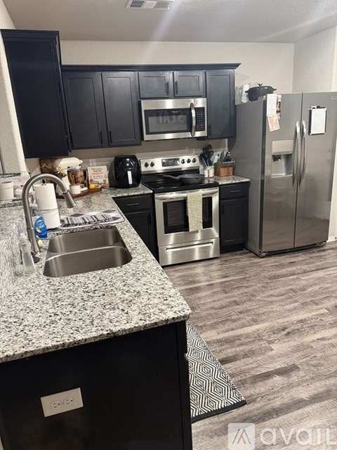A kitchen with black cabinets and a stainless steel refrigerator.