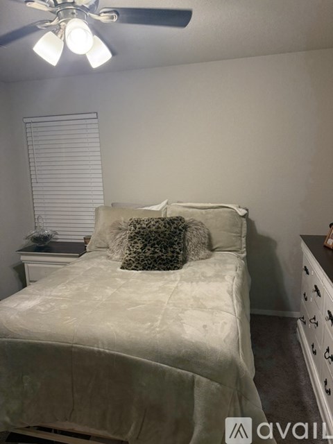 A bedroom with a bed, dresser, and ceiling fan.
