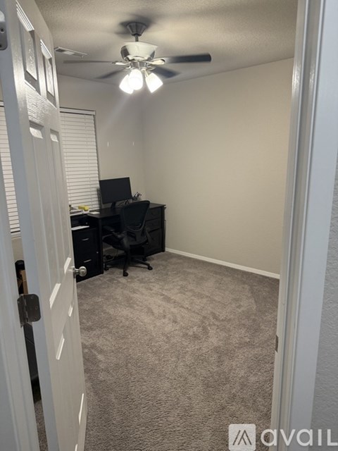 A room with a ceiling fan and a desk with a computer.