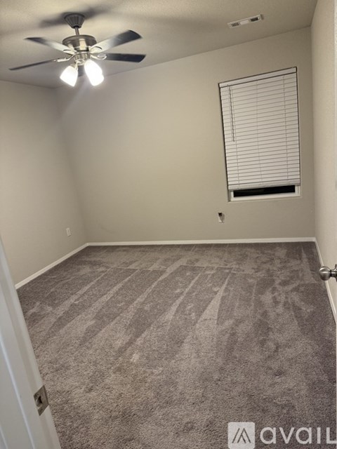 A room with a ceiling fan and carpeted floor.