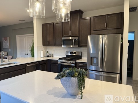 A modern kitchen with a white countertop and stainless steel appliances.