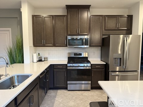A kitchen with dark brown cabinets and stainless steel appliances.