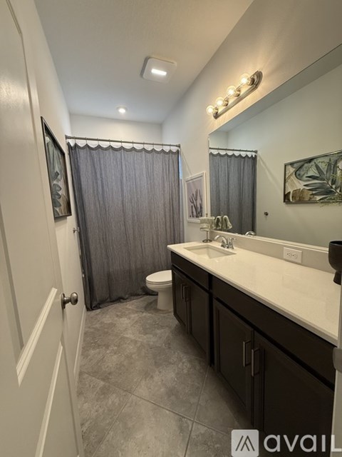 A bathroom with a toilet, sink, and mirror.