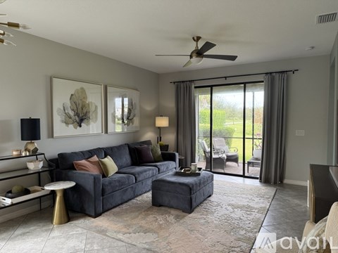 A living room with a grey couch, a coffee table, and a ceiling fan.