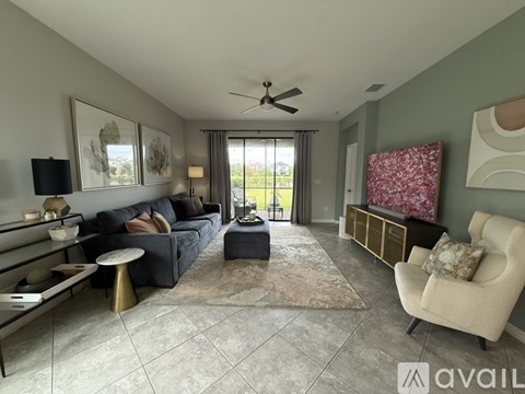 A living room with a dark blue couch, a white chair, and a rug.