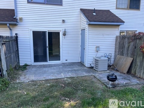 A backyard with a patio, a grill, and a fence.