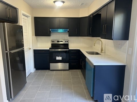A kitchen with black cabinets and a stainless steel refrigerator.