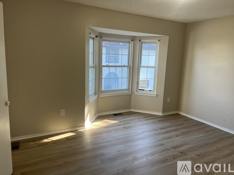 A room with wooden flooring and a large window with a view of the sky.