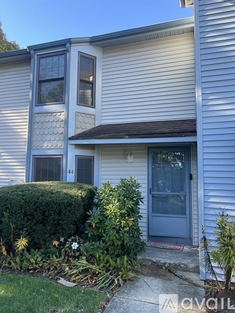 A house with a blue door and windows is numbered 44.