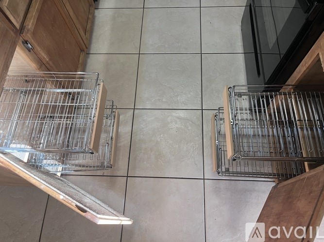 Two metal racks with glasses on them are on a tiled floor.