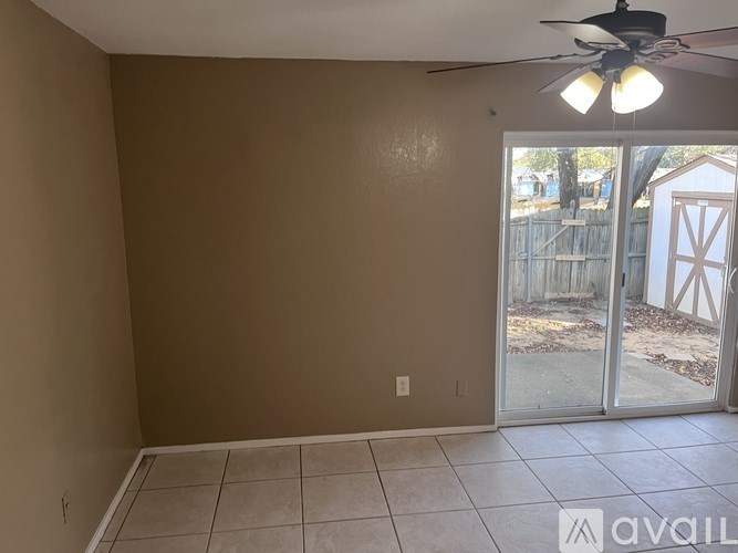 A room with a ceiling fan and sliding glass doors.
