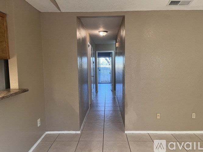 A long hallway with a light on the ceiling and a door at the end.