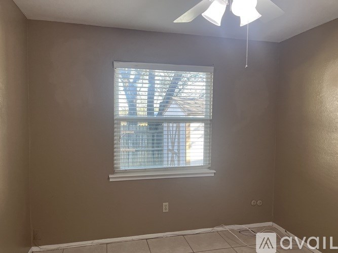A room with a window and a fan on the ceiling.