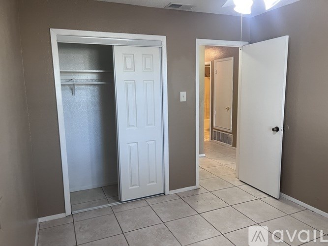 A room with two white doors, one open, and a tiled floor.