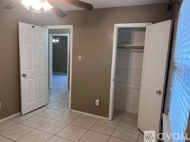 A room with a white door, a brown door, and a ceiling fan.