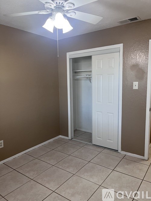 A room with a white door and a ceiling fan.