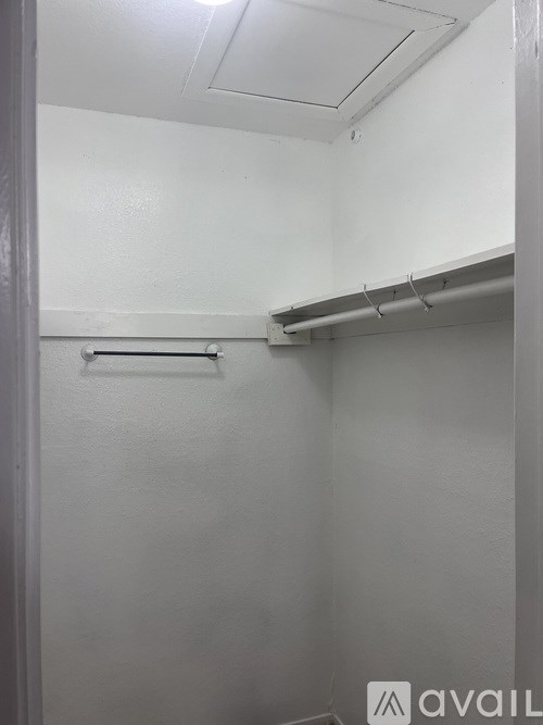 A white wall with a shelf and hooks.