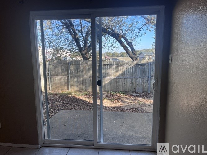 A glass door with a handle is open and shows a backyard.