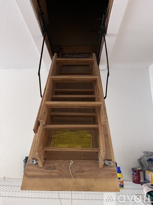 A wooden staircase with a metal railing is being installed in a room.